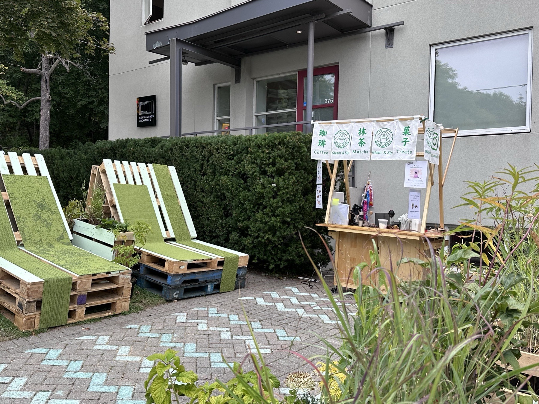 Outdoor event space with handmade wooden seating, greenery and a small market counter