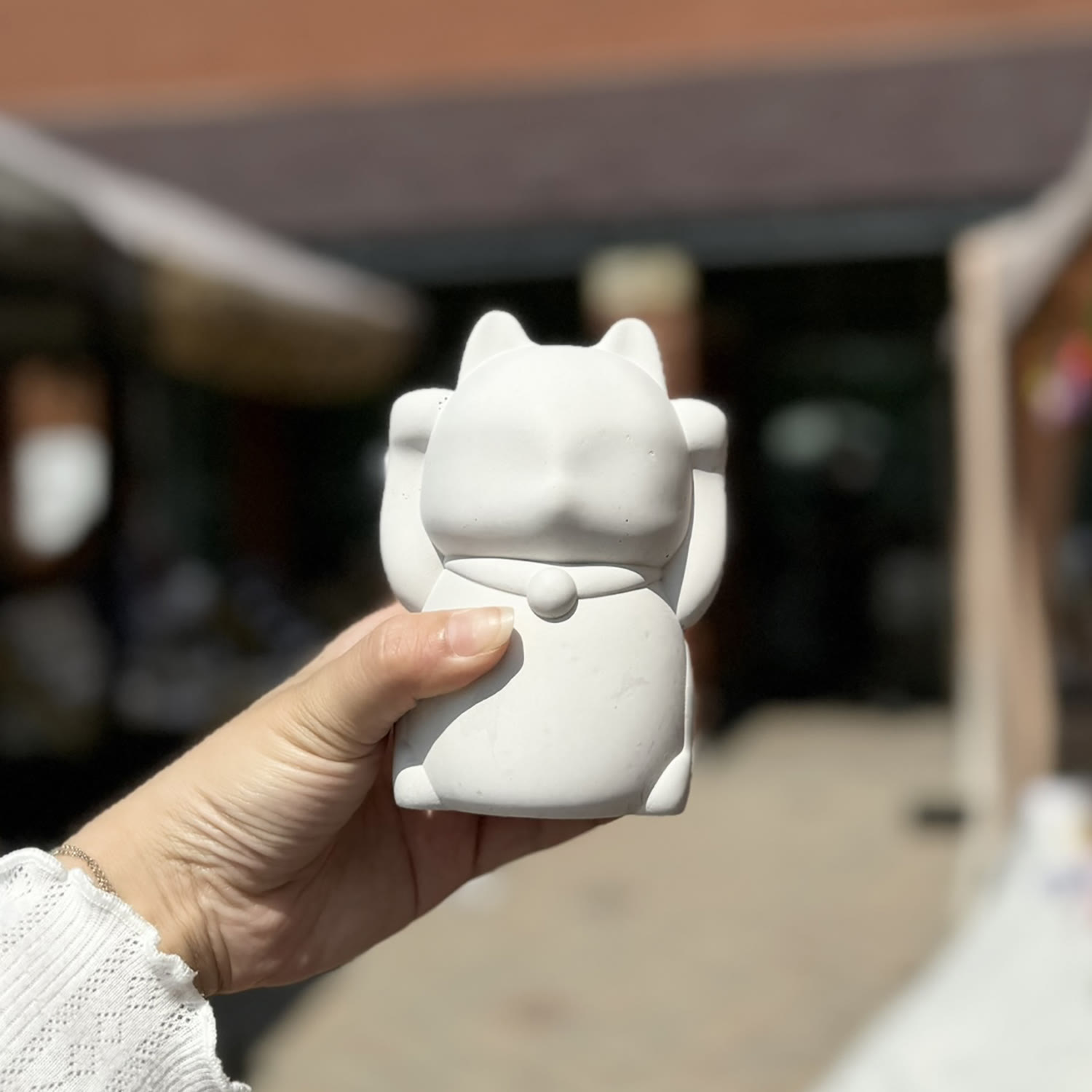 A white concrete Maneki-neko held outdoors, submitted by All Goods of Concrete